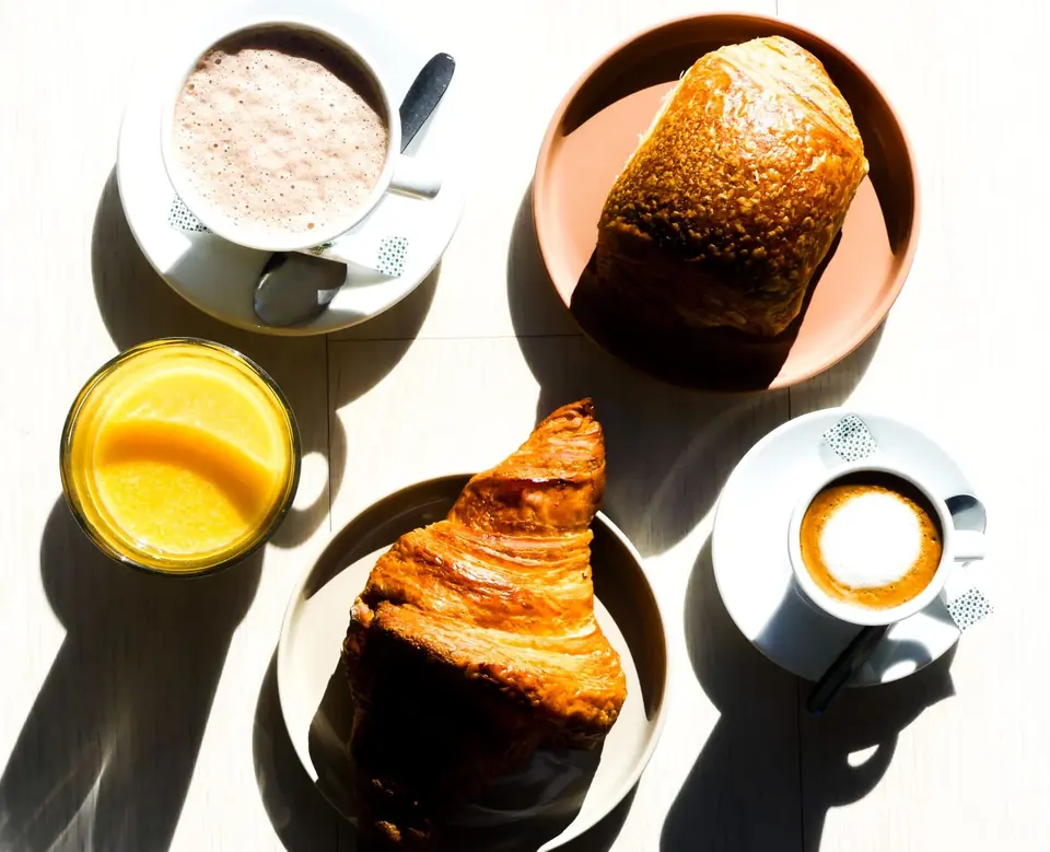 Croissants, jus d'orange et cafés photographiés en lumière naturelle